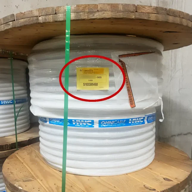 A spool of flexible conduit in one of Loeb Electric's warehouses. A yellow identification label has been attached that describes the project and PO number associated with the material.