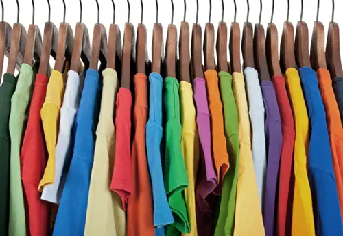 Colorful T-shirts hanging on a display rack. Standard LED color rendering dulls their color.