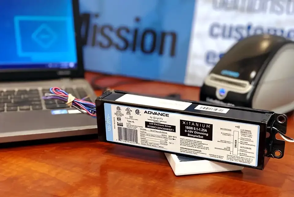 Advance programmable driver (by Signify) placed on top of a computer interface device with a laptop in the background. The laptop shows Signify's driver program open and ready to go.