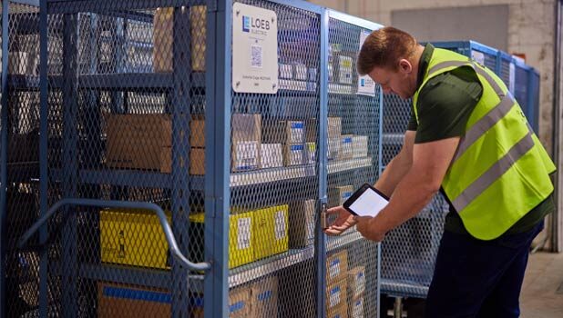 A Loeb Electric warehouse employee checks the lock on a blue vendor-managed inventory cart.