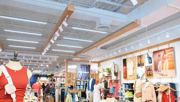 A brightly-lit clothing store. Linear LED lighting fixtures as well as LED track lighting illuminate the retail floor.